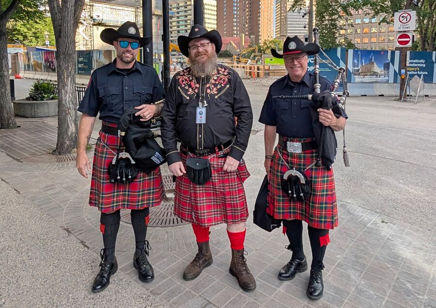 Three people in kilts and black cowboy hats at the Stampede Parade