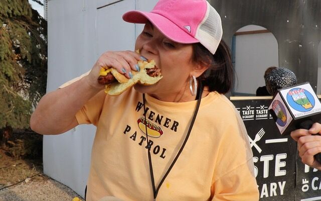 Anita wearing a yellow shirt eating a hot dog